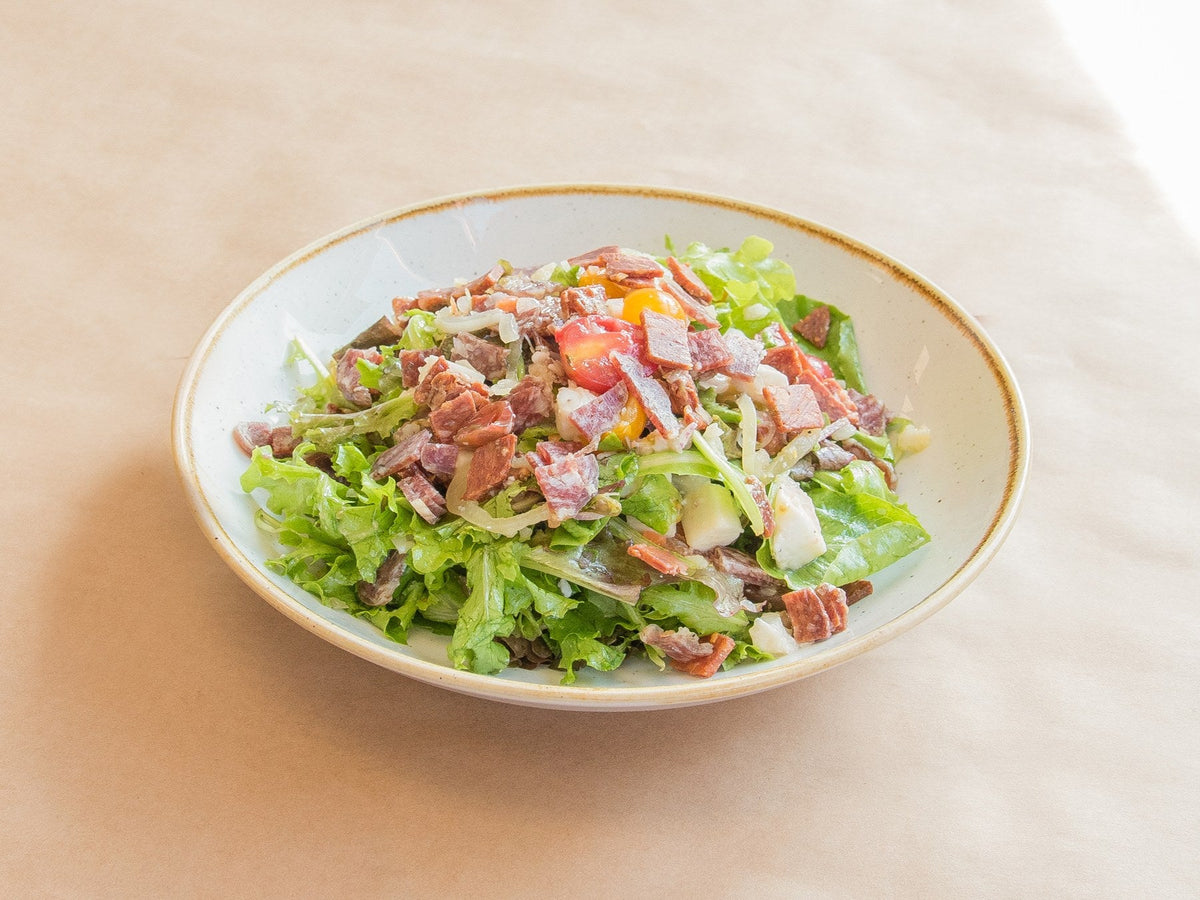 Salami chop salad with mixed greens, chopped salami, cherry tomatoes and mozzarella