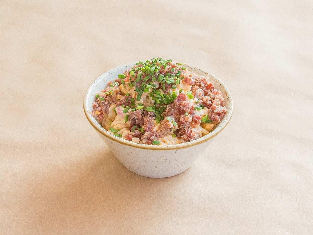 Salami end pasta salad topped with chopped salami and chives