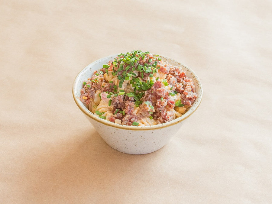 Salami end pasta salad topped with chopped salami and chives