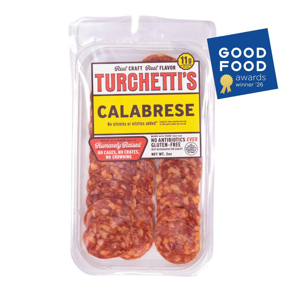 Award-winning Turchetti's Calabrese sliced salami in a clear plastic clamshell container, shown on a white background with a blue 2026 Good Food Awards badge in the top right corner.